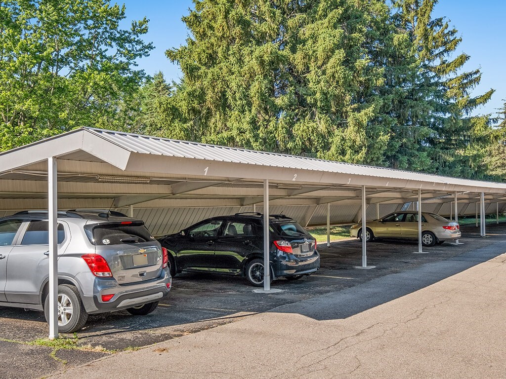 A carport with three cars parked underneath.