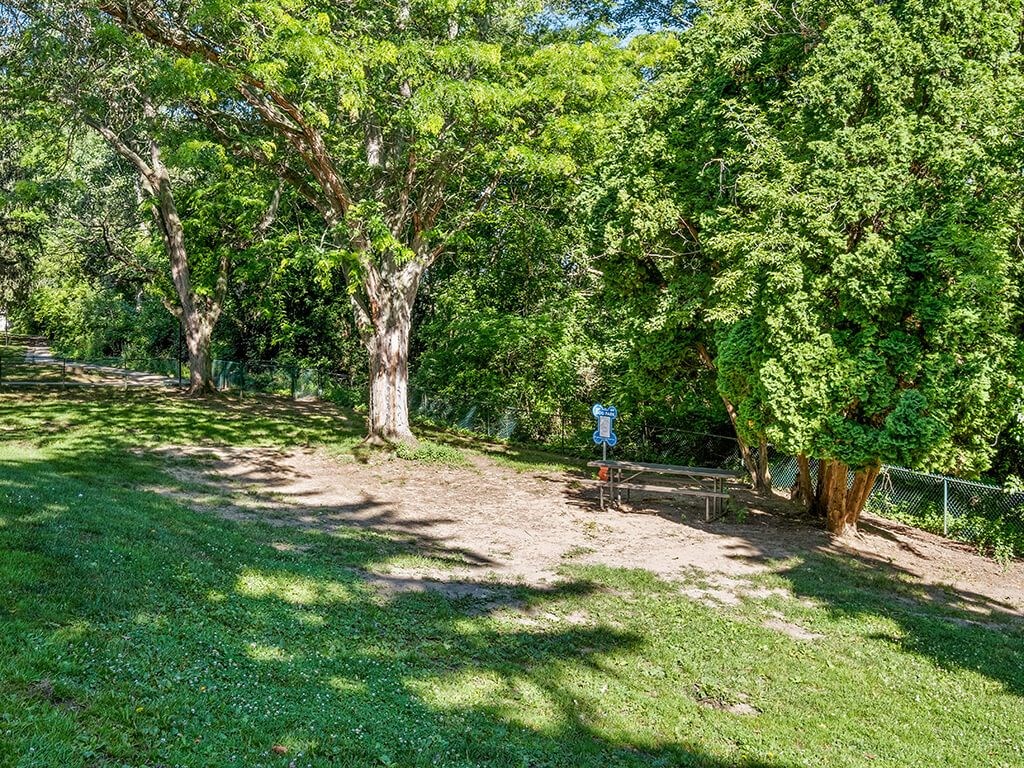 A park with a picnic table and a blue sign.