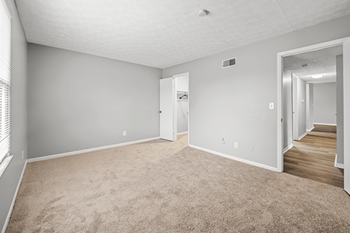 A room with a carpeted floor and a door on the left side.