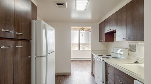 A kitchen with a white refrigerator and brown cabinets.