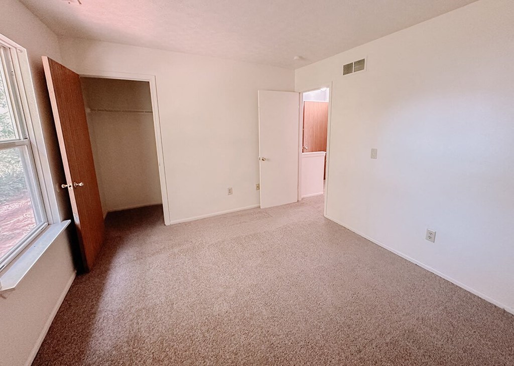 a bedroom with a carpeted floor and a door to a closet