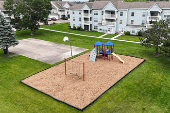 A playground with a slide, swings and a basketball hoop.