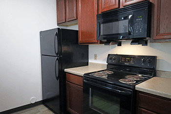 A black microwave is mounted above a black stove in a kitchen.