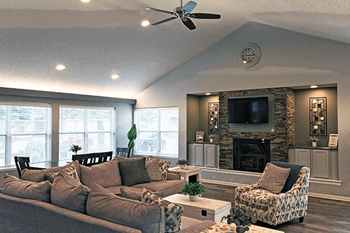 A living room with a grey couch, a chair, and a fireplace.