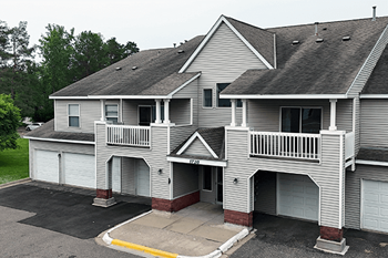 A grey two-story house with a balcony on the second floor.