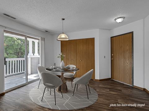 A dining room with a table set for two and a view of a deck outside.