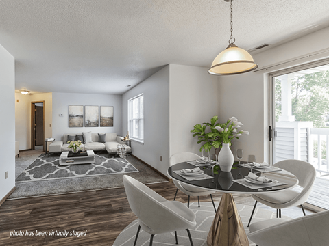 A modern living room with a glass table and white chairs.