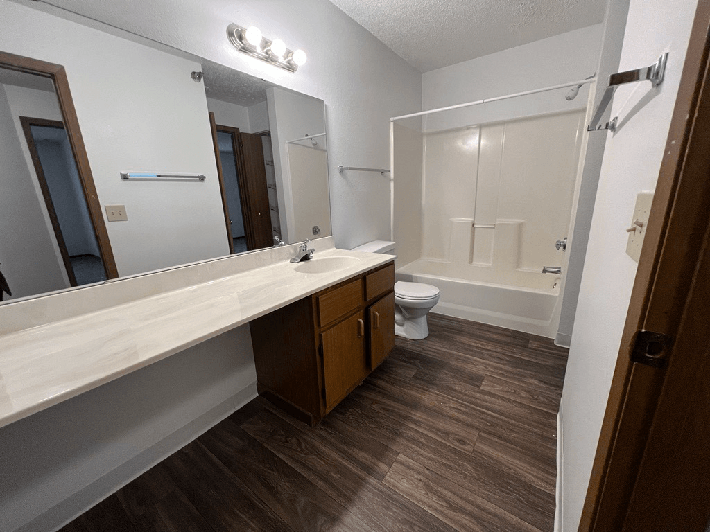 A bathroom with a toilet, sink, and mirror.