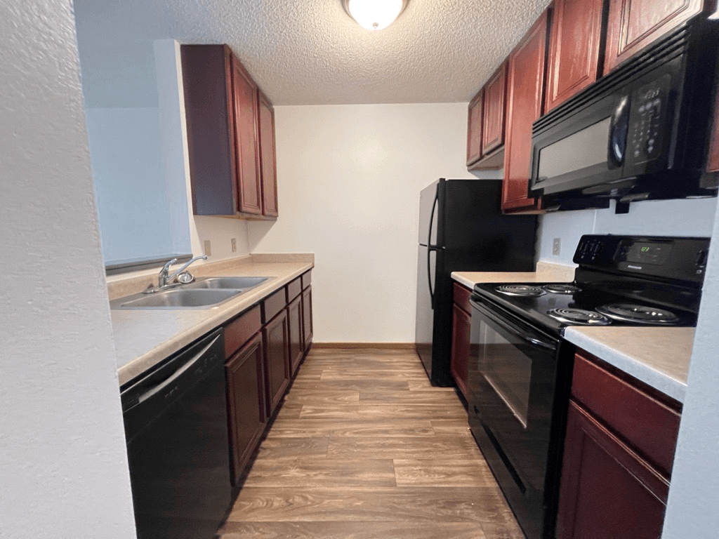 A kitchen with black appliances and brown cabinets.
