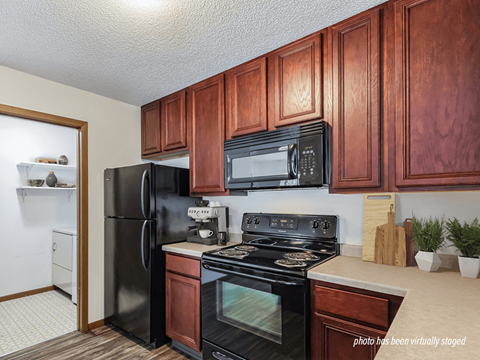 A kitchen with black appliances and wooden cabinets.