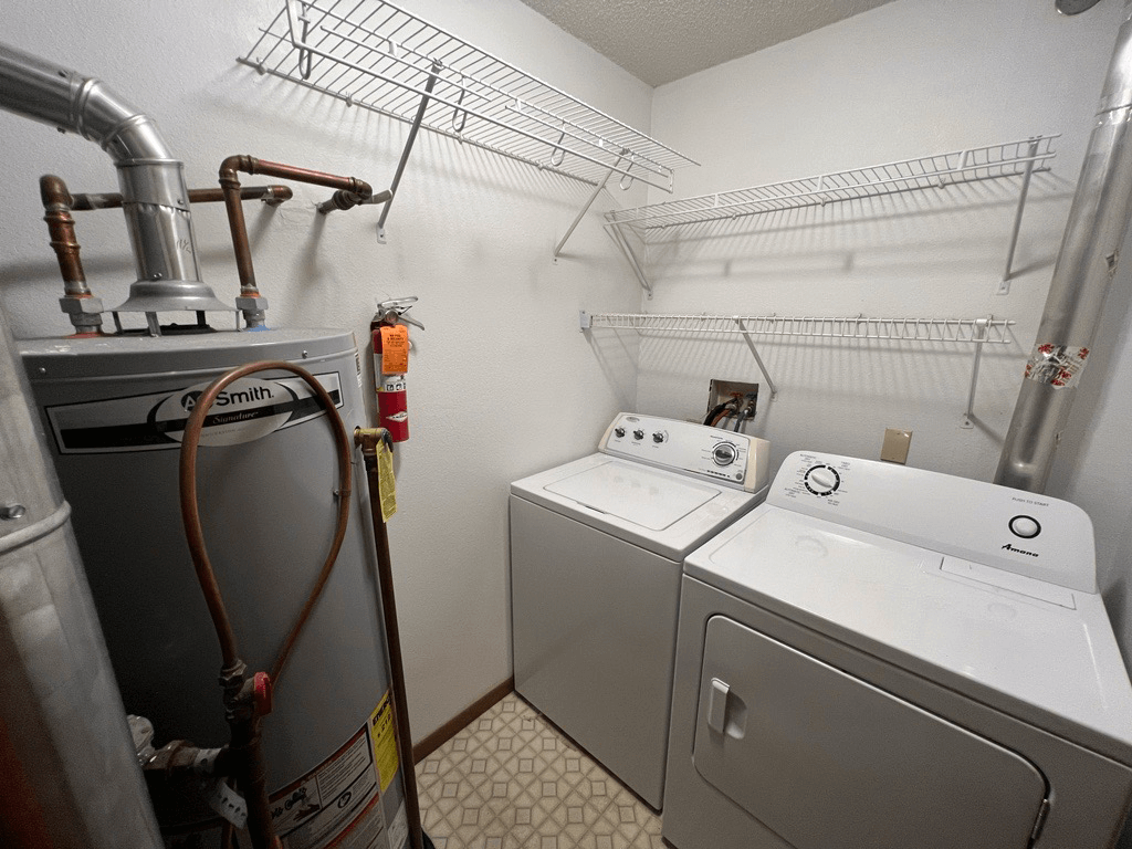 A laundry room with a washer and dryer and a hose.