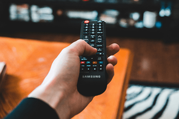 A hand is holding a Samsung remote control.