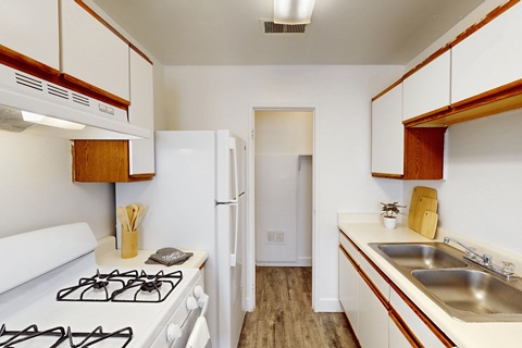A kitchen with a white gas stove and white cabinets.