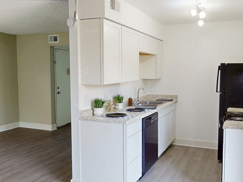 A kitchen with white cabinets and a black refrigerator.