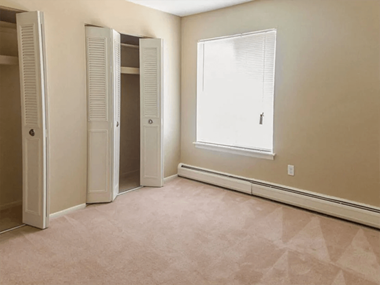 a bedroom with a large window and two closets