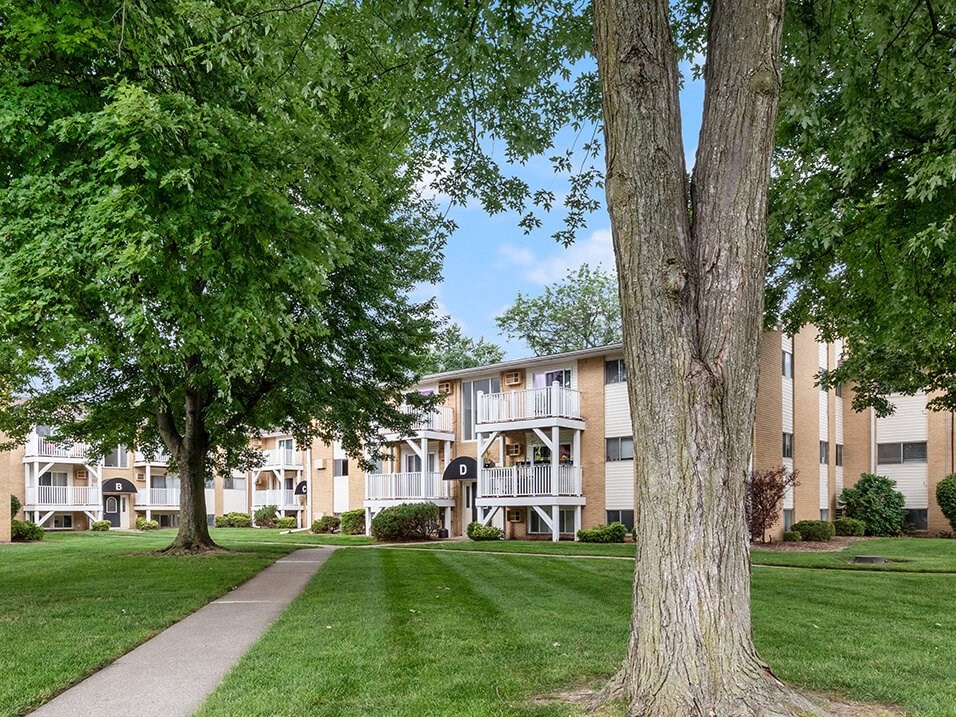 an apartment building with trees and a sidewalk