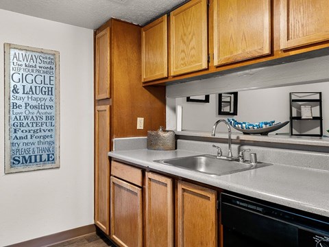 A kitchen with wooden cabinets and a poster on the wall with positive words.