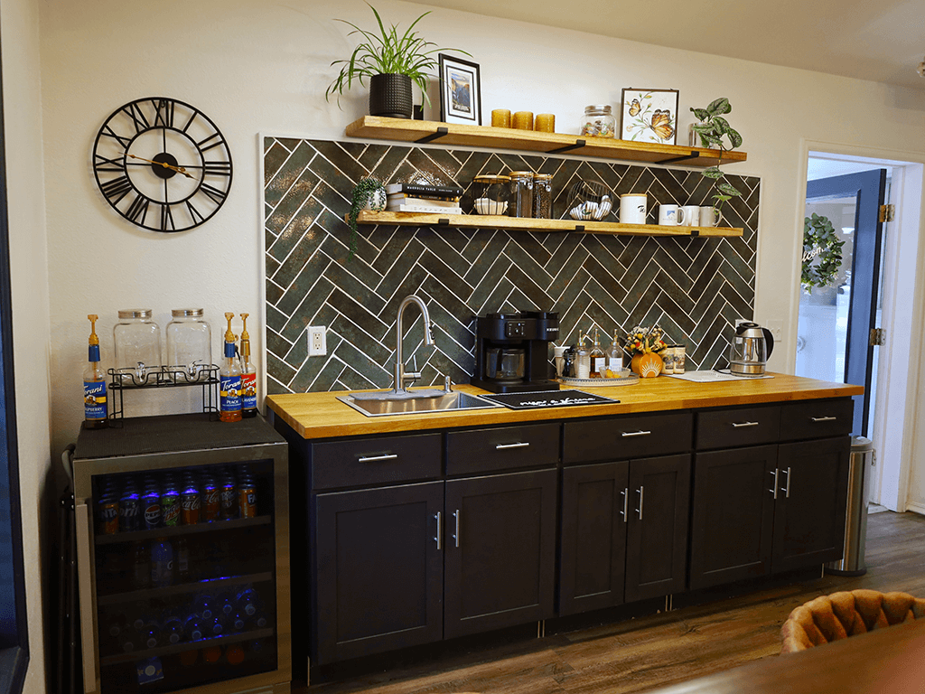 A kitchen with a black and white tile backsplash and wooden countertop.