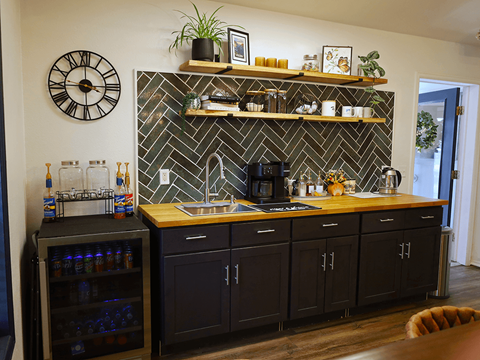 A kitchen with a black and white tile backsplash and wooden countertop.