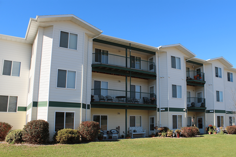 Apartment building with green bushes in front.