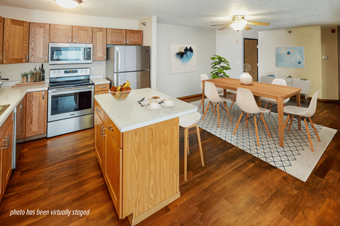A kitchen with wooden cabinets and a wooden island with chairs around it.