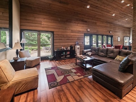 a large living room with leather furniture and wooden walls