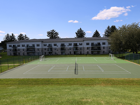 A tennis court is located in front of a large building.