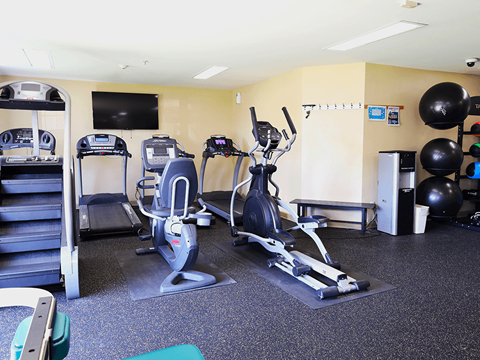 A gym with a variety of equipment including treadmills, exercise bikes, and weights.