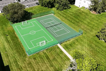 A green tennis court is surrounded by a green fence.