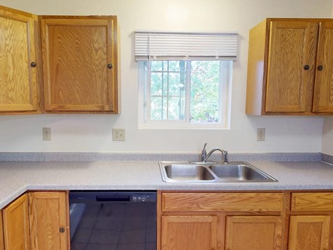 A kitchen with wooden cabinets and a window.