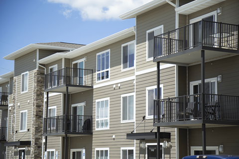 A row of apartment buildings with balconies and black railings.