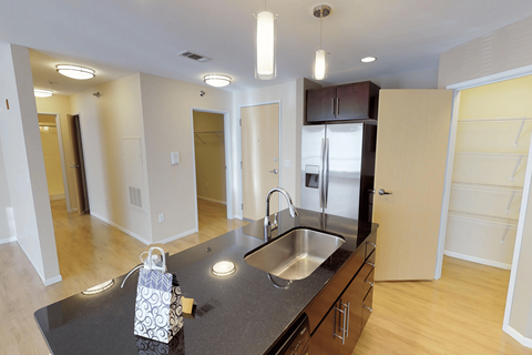 A kitchen with a black counter top and a white bag on it.