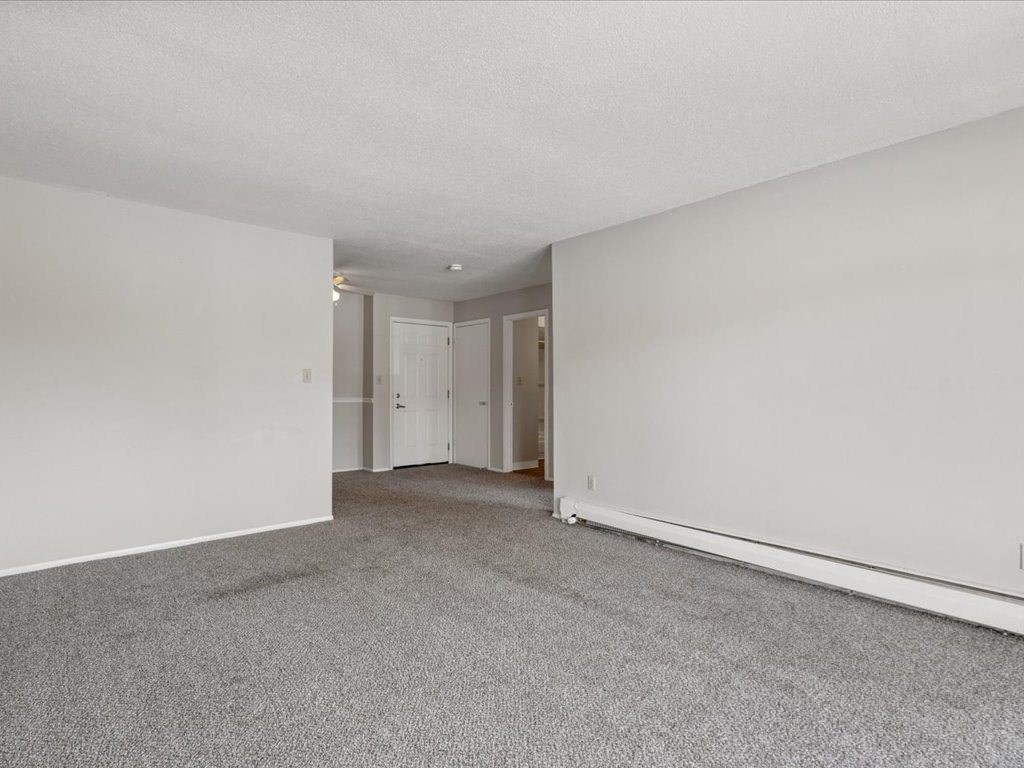 an empty living room with white walls and carpet