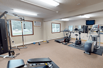 A spacious gym with a variety of equipment including treadmills, stationary bikes, and weight machines.