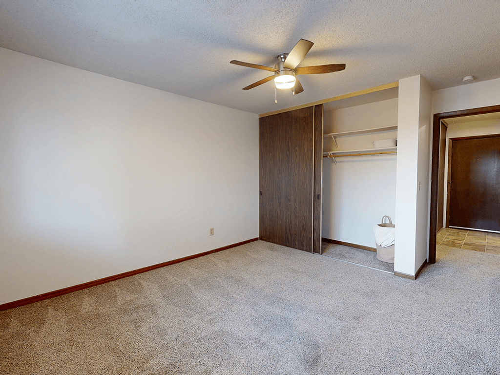 A room with a ceiling fan and a carpeted floor.