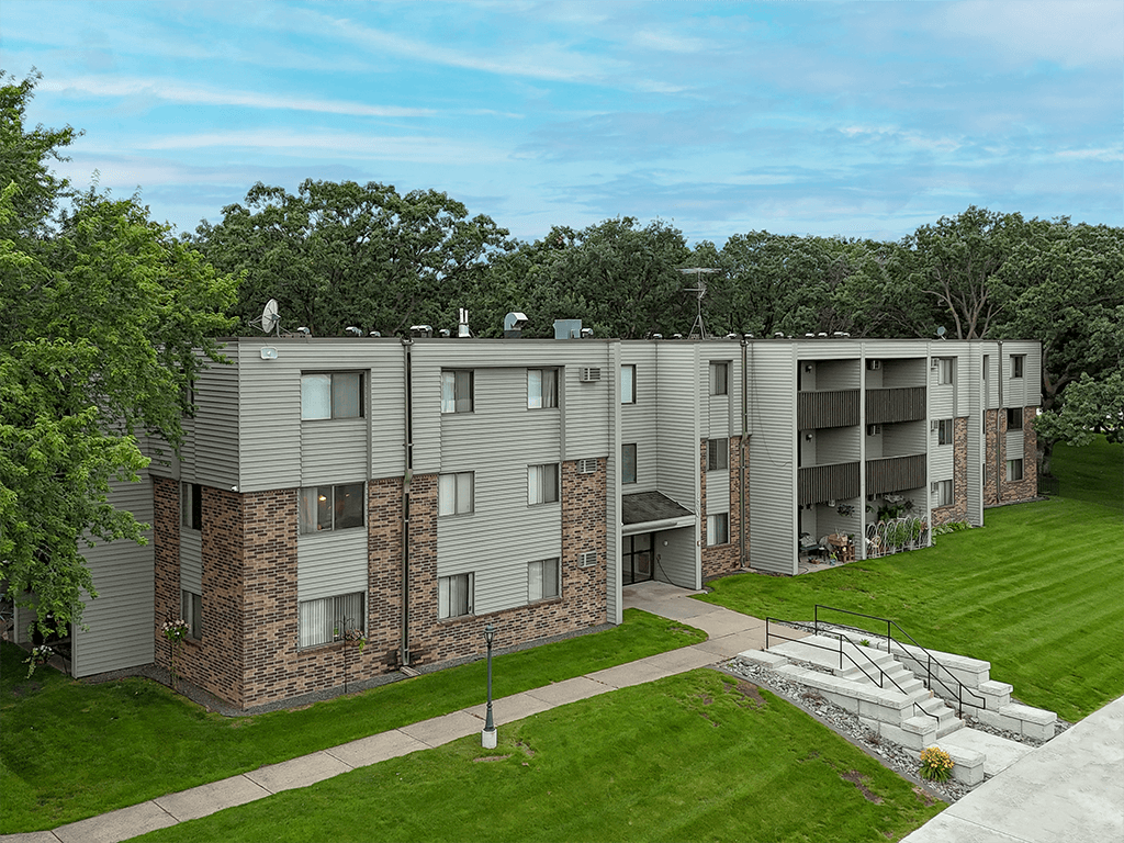 A large apartment complex with a green lawn in front.