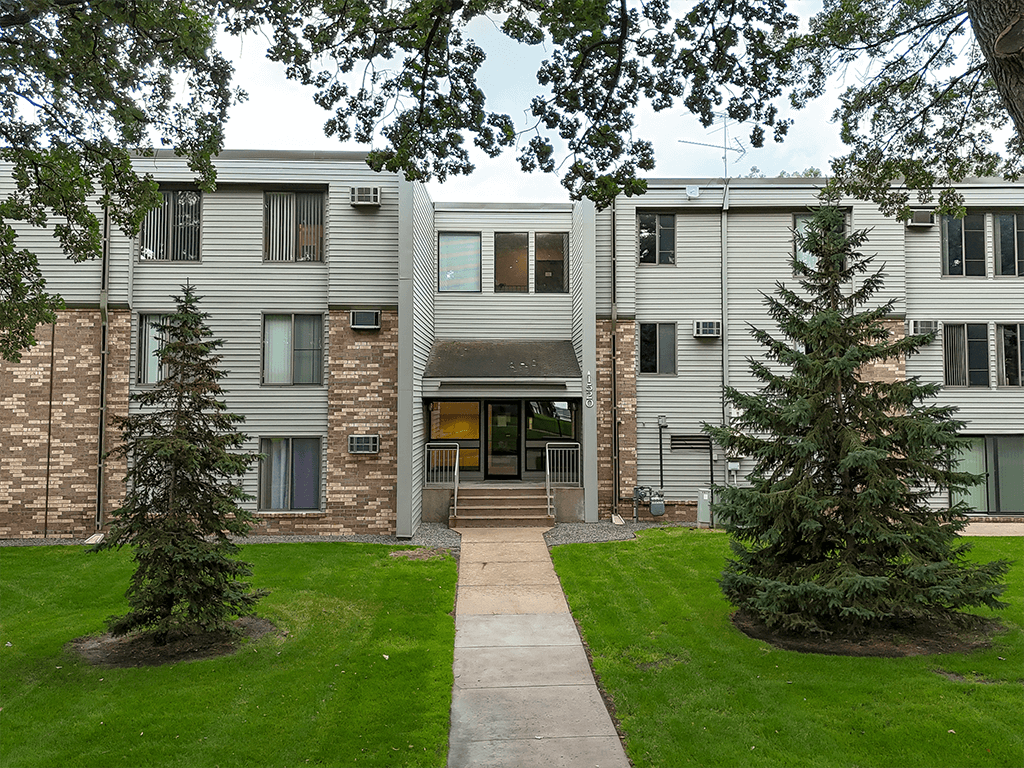 A building with a grey exterior and a brown brick wall.
