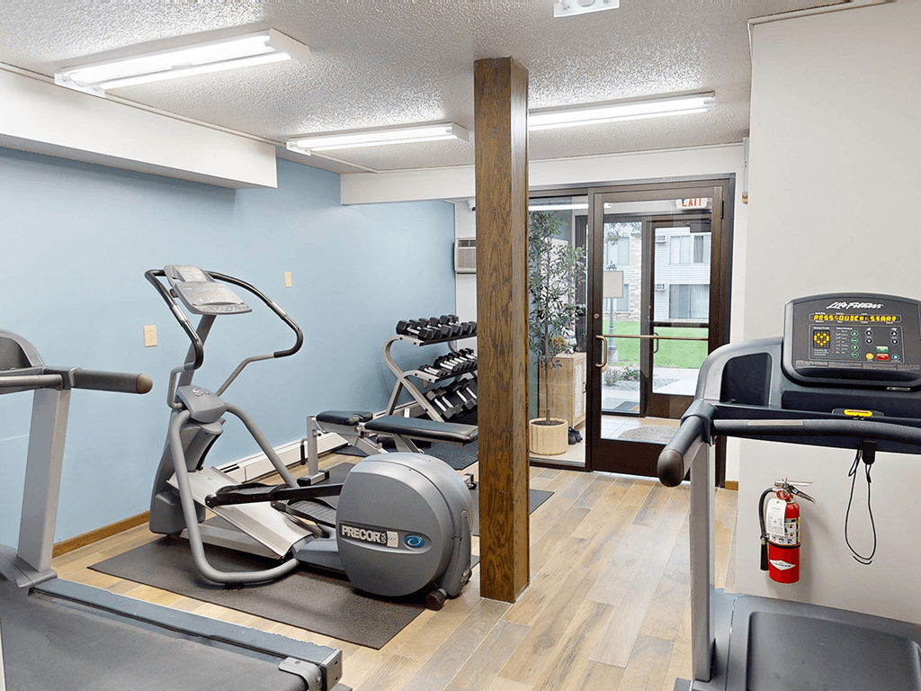 A gym with a treadmill, elliptical trainer and a stationary bike.
