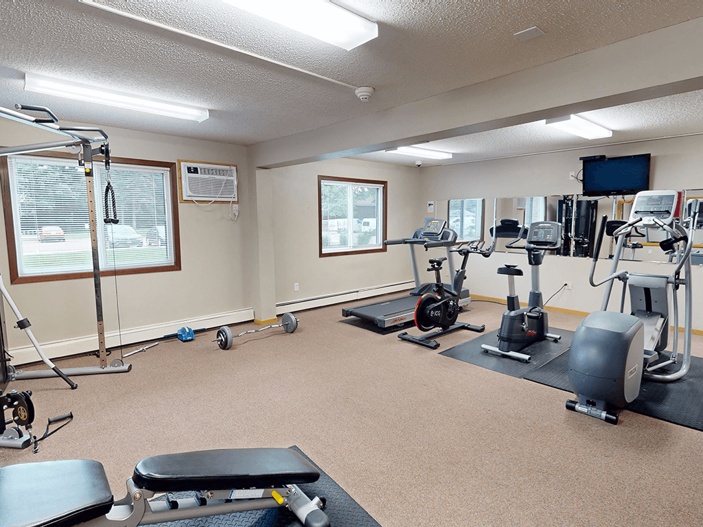 A spacious gym with a variety of equipment including treadmills, stationary bikes, and weight machines.