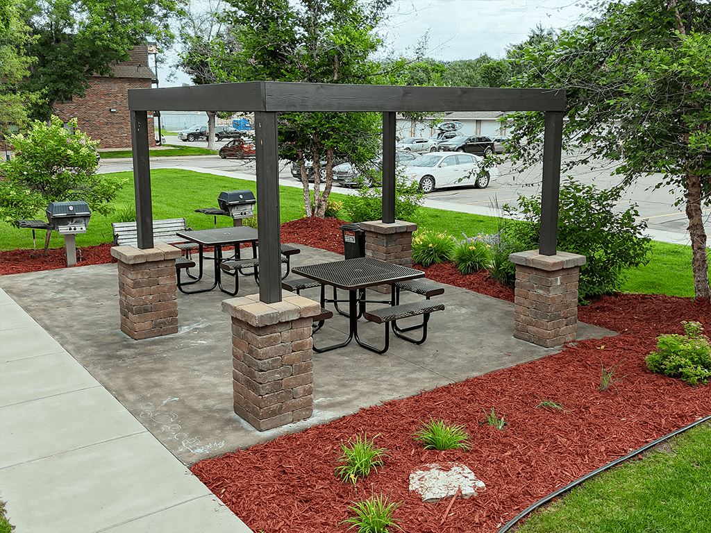 A patio with a table and chairs under a wooden pergola.