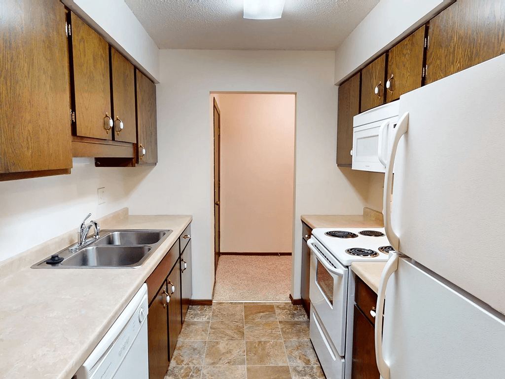 A kitchen with a white refrigerator, white stove, and a sink.