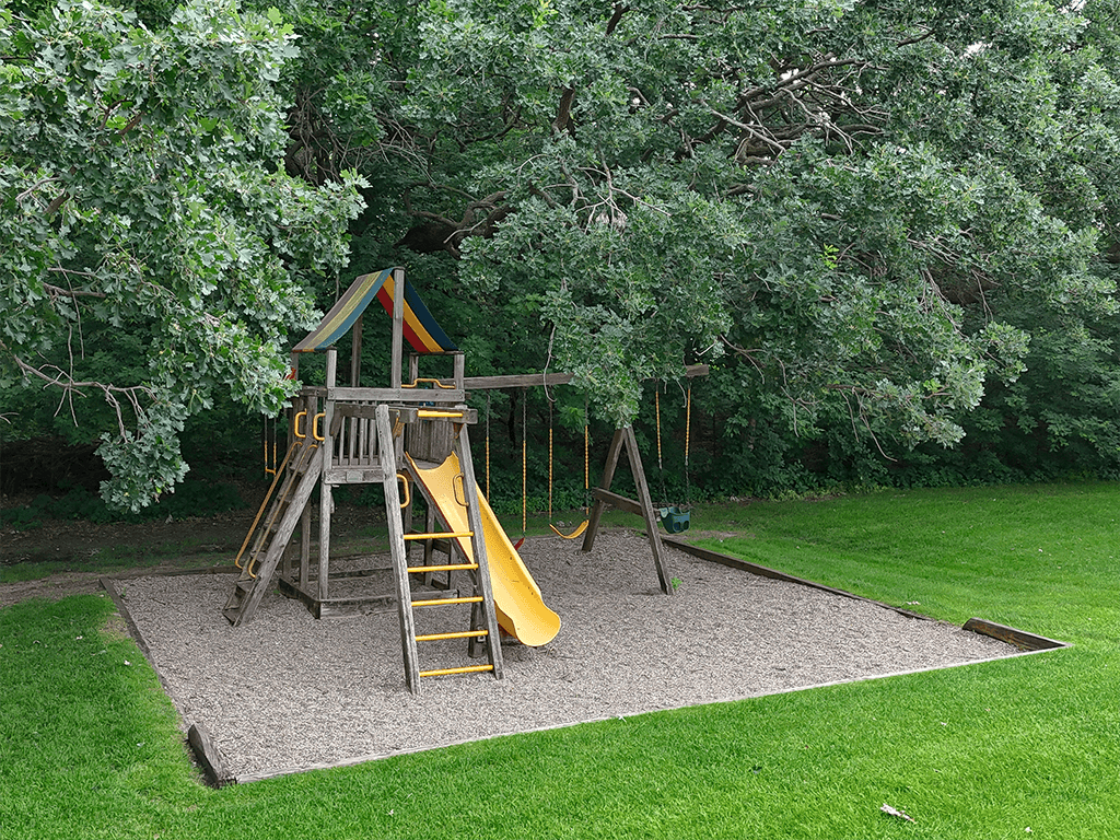 A playground with a yellow slide and a wooden structure.