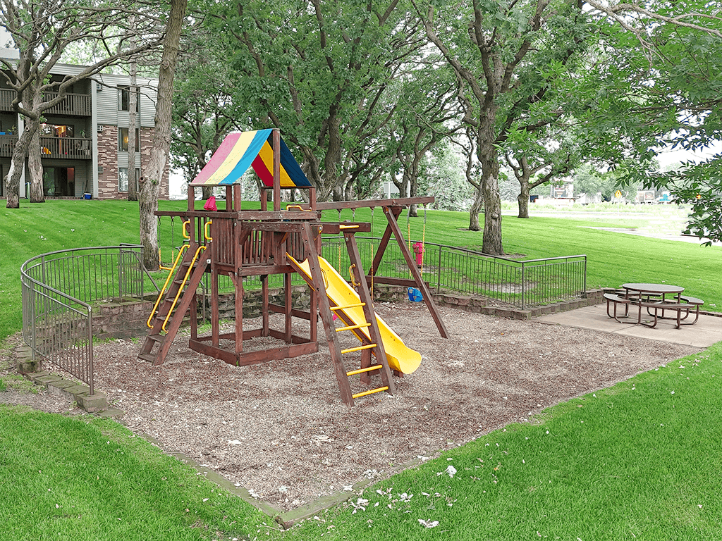 A playground with a wooden structure and a yellow slide.