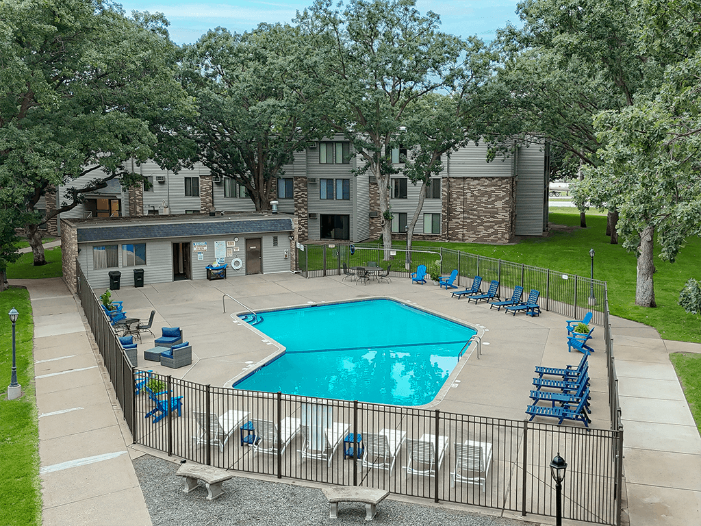 A pool surrounded by a fence and chairs.