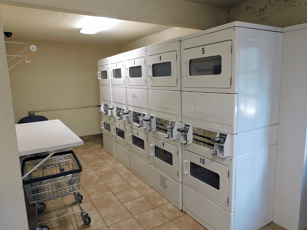 a row of washers and dryers with folding station on-site at the oaks at bentonshire