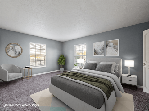 A bedroom with a large bed and a chair.