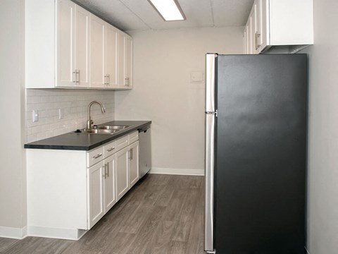 a kitchen with a black refrigerator and white cabinets