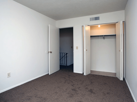 A room with a carpeted floor and a closet with a light on.