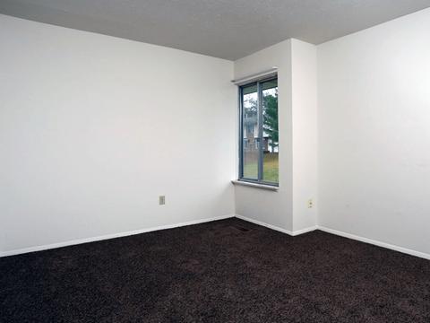 A room with a window and carpeted floor.