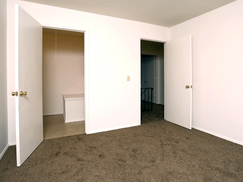 A room with a carpeted floor and two doors.